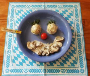 Semmelknödelinos mit Champignonrahmsoße als Gesicht am Teller dekoriert